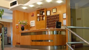 A reception area with a wooden counter, a clock, and a vase of flowers. - Hotel Ismaele (Chiusi)