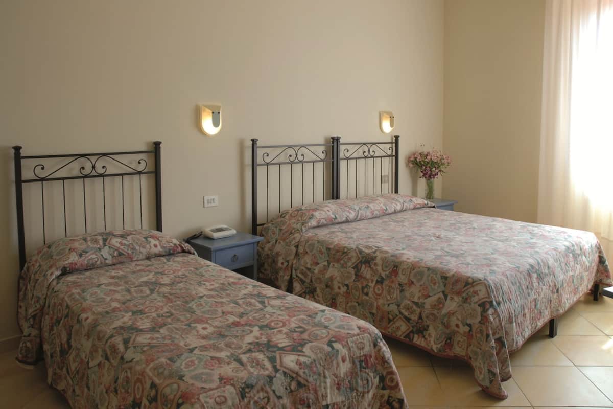 A bedroom with two beds, each with a patterned bedspread, a nightstand, and a wall-mounted light fixture.
