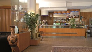 A hotel lobby with a reception desk, a bar area, a large vase, and a patterned rug. - Hotel Ismaele (Chiusi)