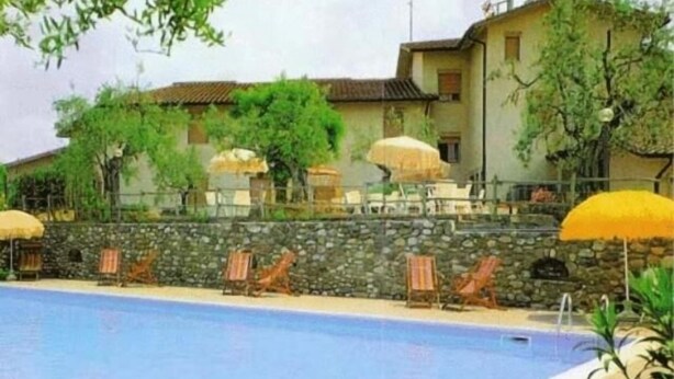 A pool area with lounge chairs and umbrellas, surrounded by stone walls and vegetation. - Hotel Ismaele (Chiusi)