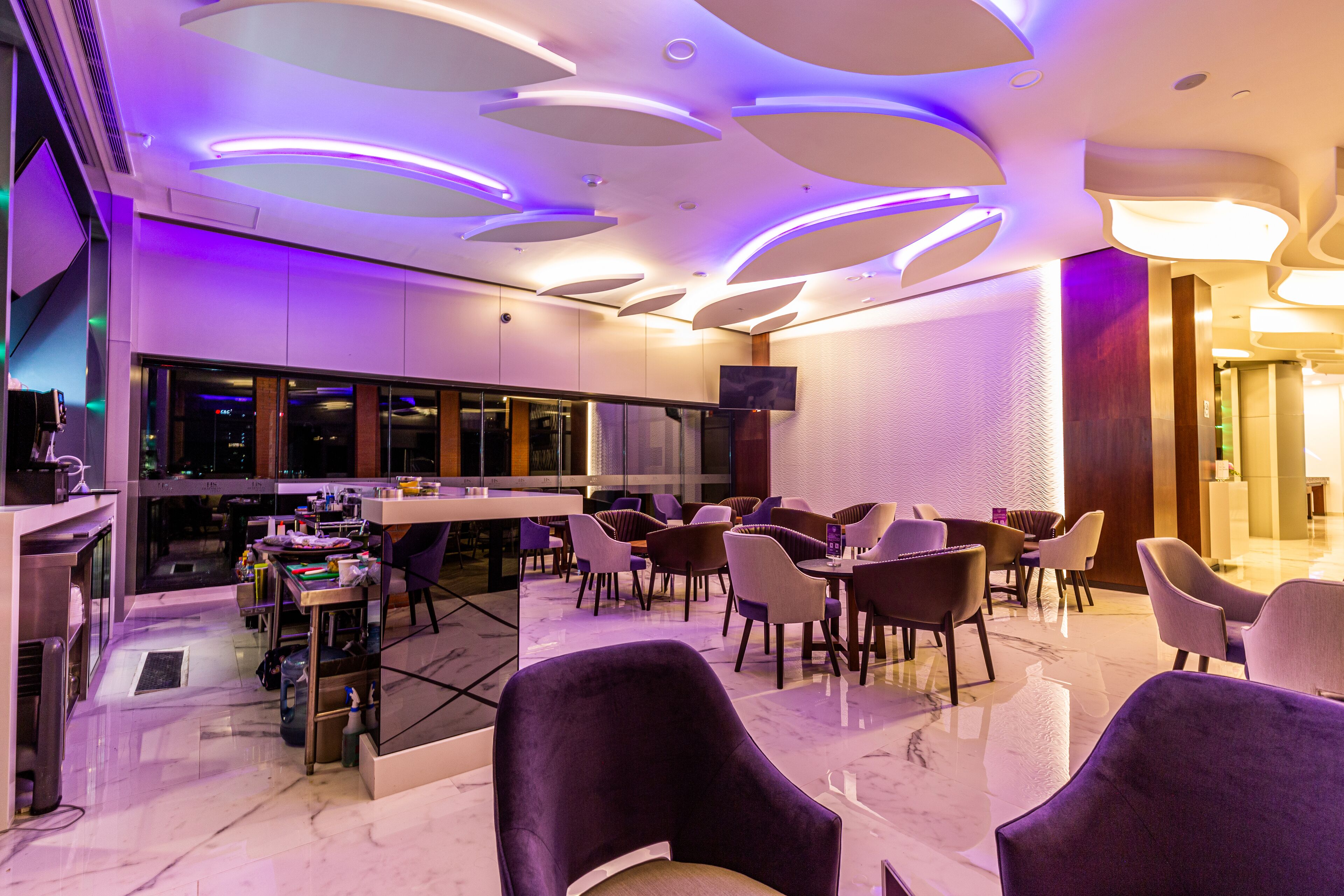 A modern hotel lobby with a bar area, seating, and a flat-screen TV.