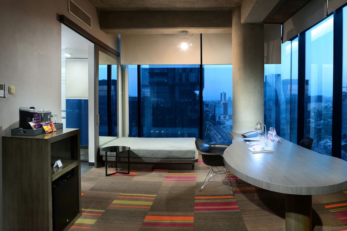 Habitación de hotel moderna con una cama grande, un escritorio y vistas a la ciudad.