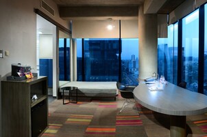 Habitación de hotel moderna con una cama grande, un escritorio y vistas a la ciudad.