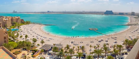 Un complejo turístico en la playa con piscina, tumbonas y vistas al océano.
