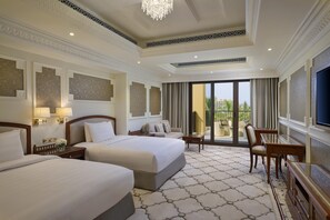 A hotel room with two beds, a sitting area with a chair and table, a large TV, and a balcony with outdoor furniture. - DoubleTree by Hilton Resort & Spa Marjan Island (Ras Al Khaimah)