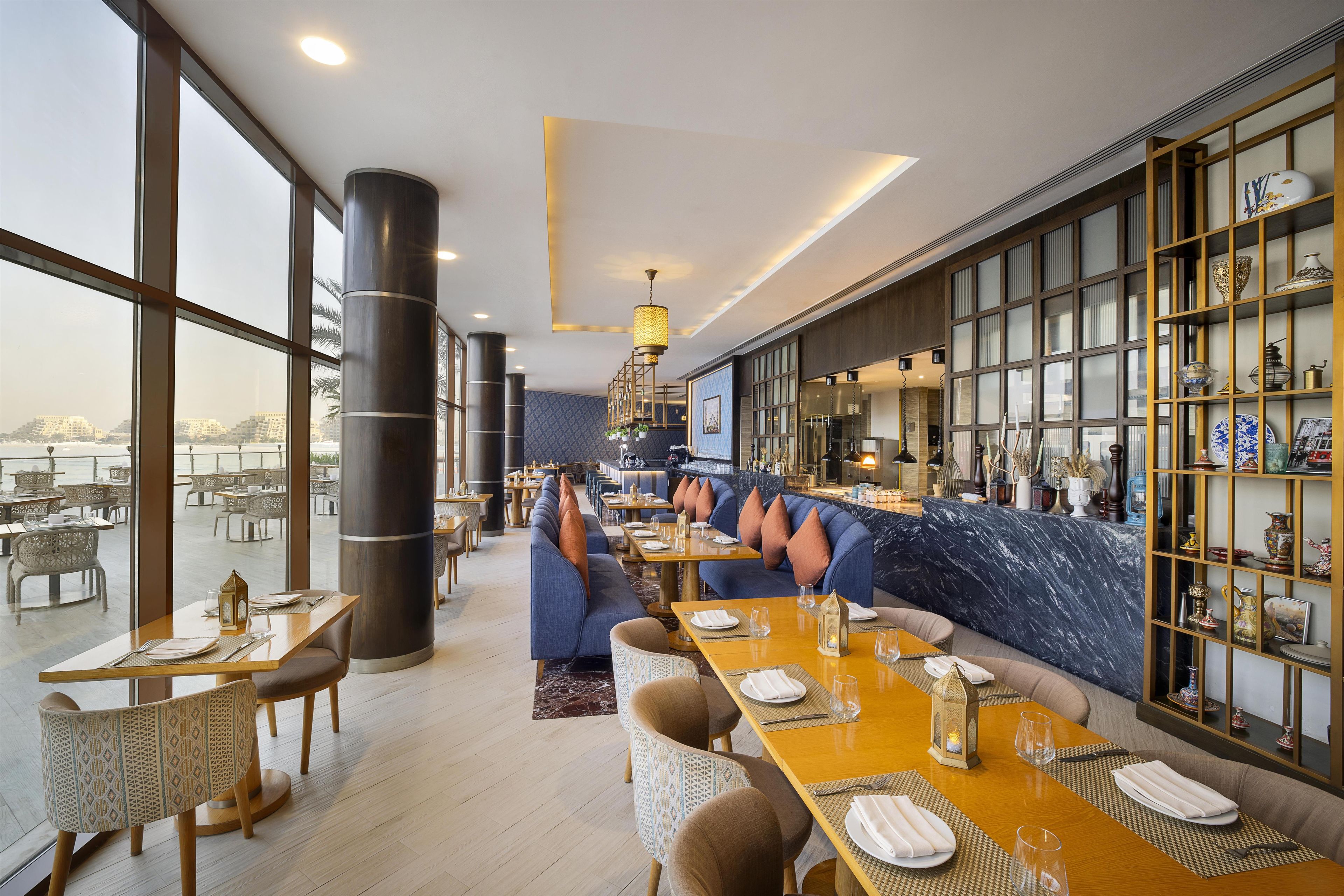 Un restaurante con techos altos, amplias ventanas y vistas a la ciudad.