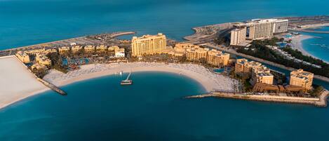 An aerial view of a coastal resort with a marina, beach, and multiple hotel buildings.