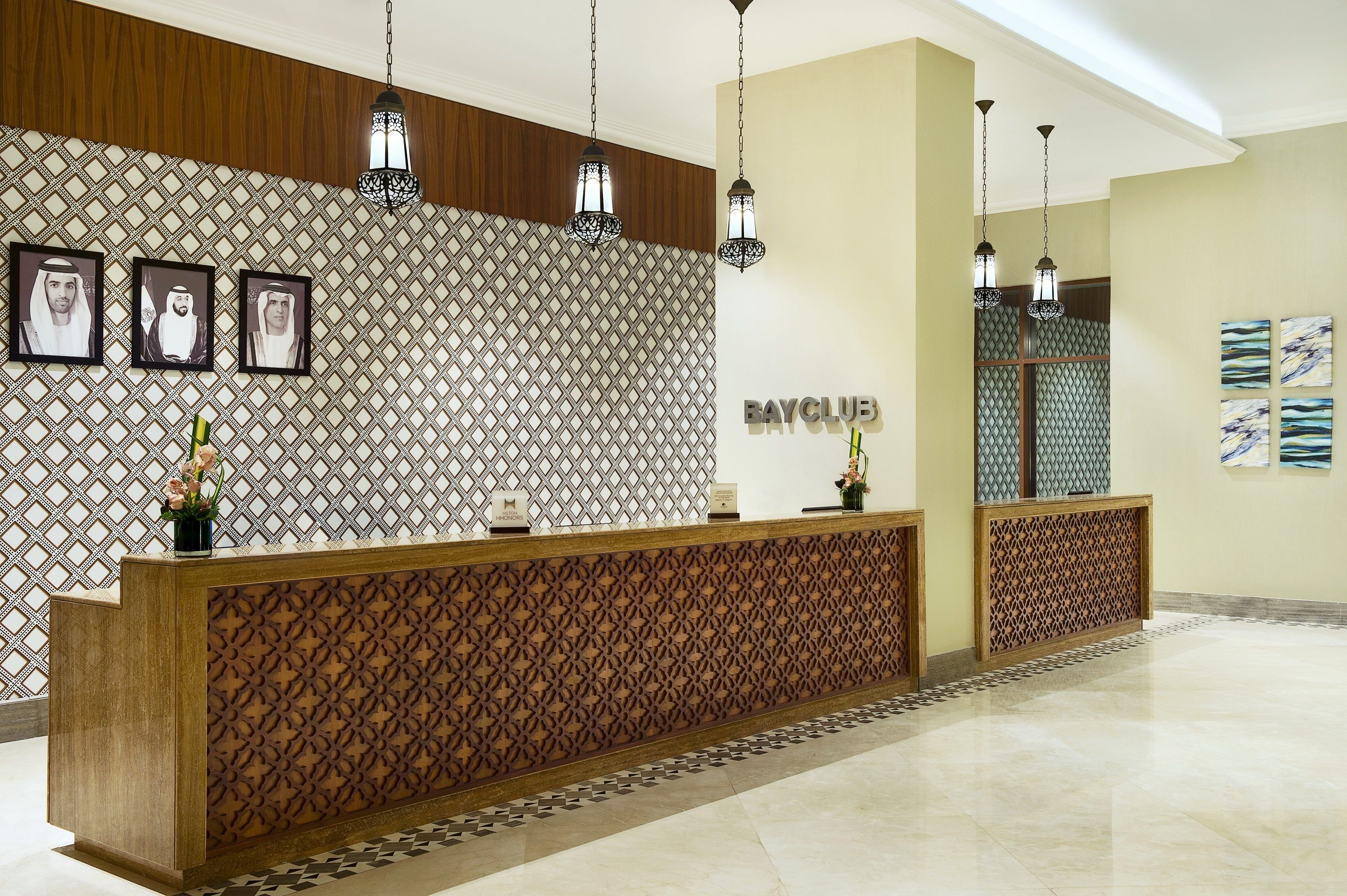 A reception area with a patterned wall, a wooden reception desk, and hanging pendant lights.