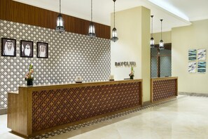 A reception area with a patterned wall, a wooden reception desk, and hanging pendant lights. - DoubleTree by Hilton Resort & Spa Marjan Island (Ras Al Khaimah)