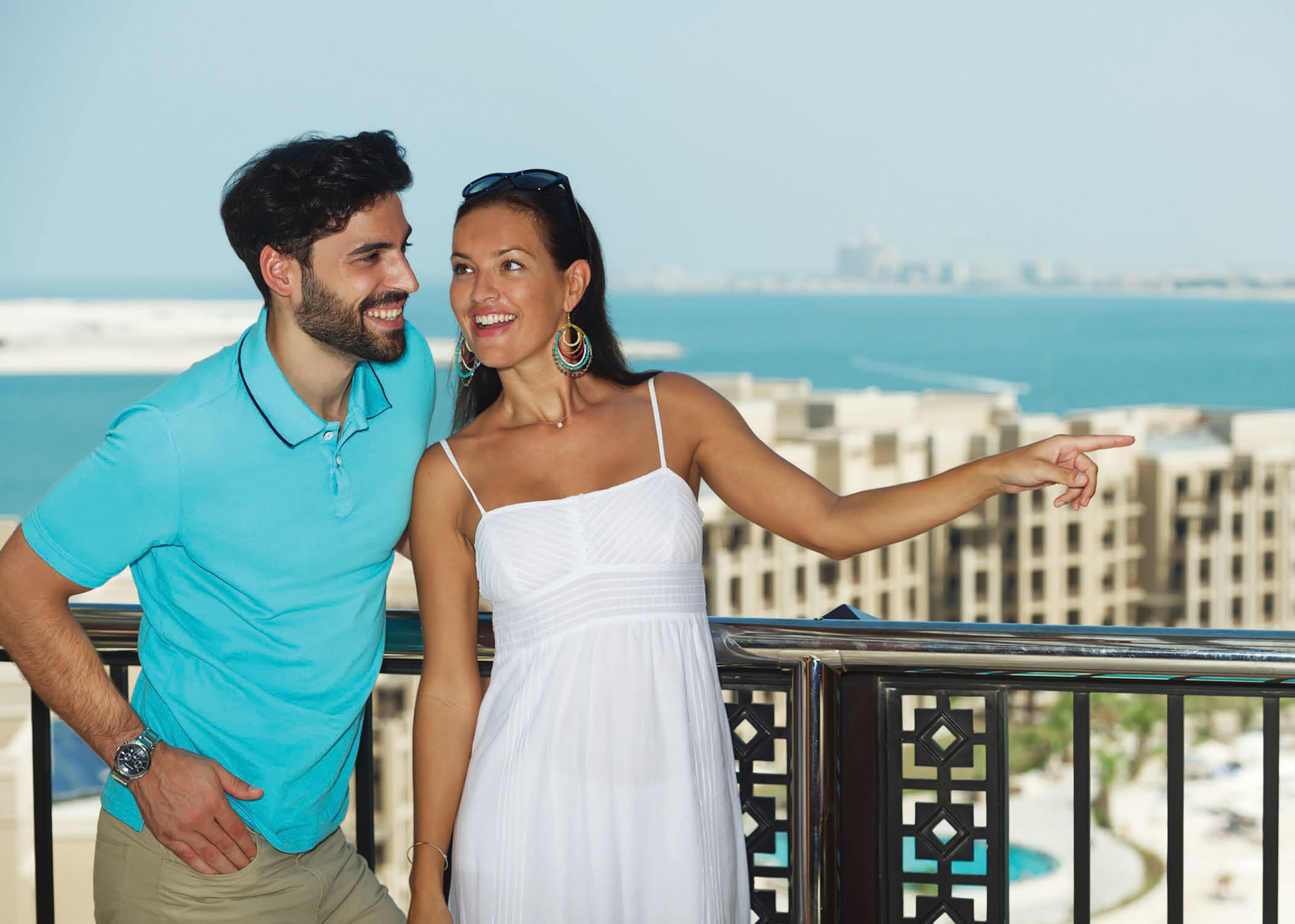 Una coppia su un balcone con vista sulla città e sul mare.