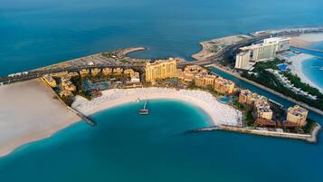 An aerial view of a coastal resort with a marina, sandy beaches, and beachfront hotels.