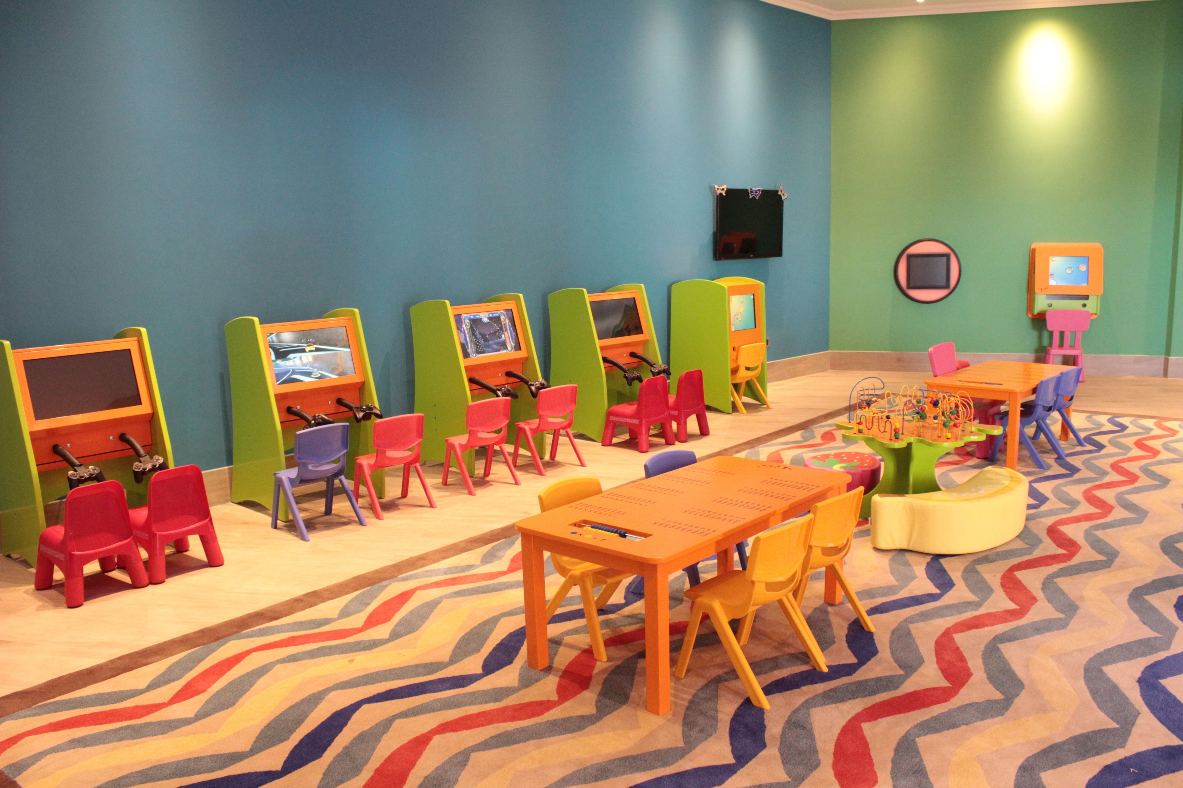 Ein Kinderspielbereich mit bunten Stühlen, Tischen und Spielestationen.