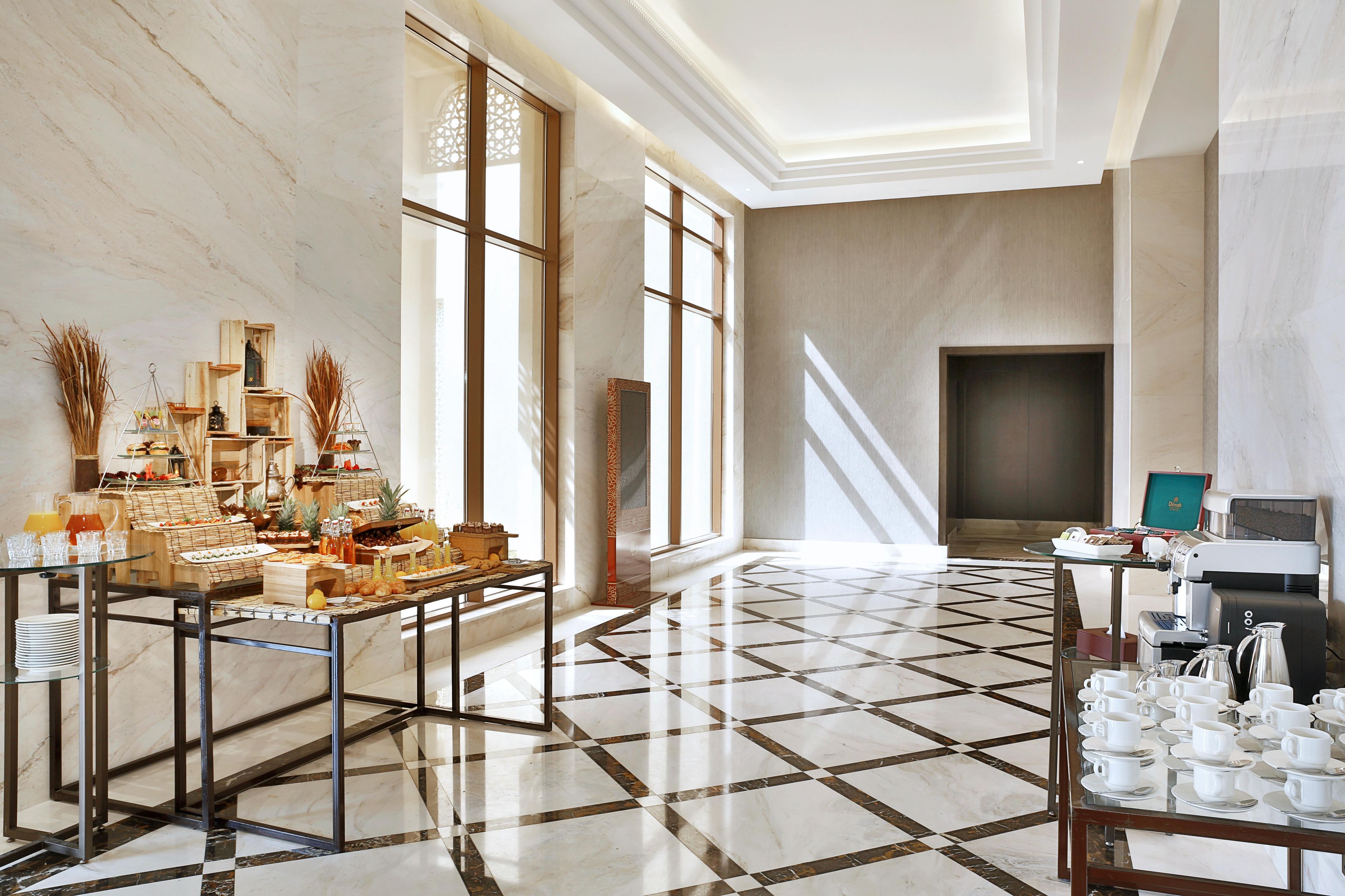 A spacious room with a marble floor, a buffet table with various food items, and a coffee station.