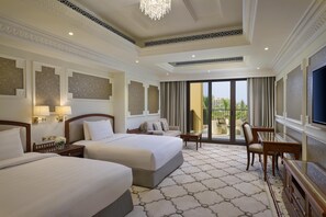 A hotel room with two beds, a balcony, a TV, and a chandelier.