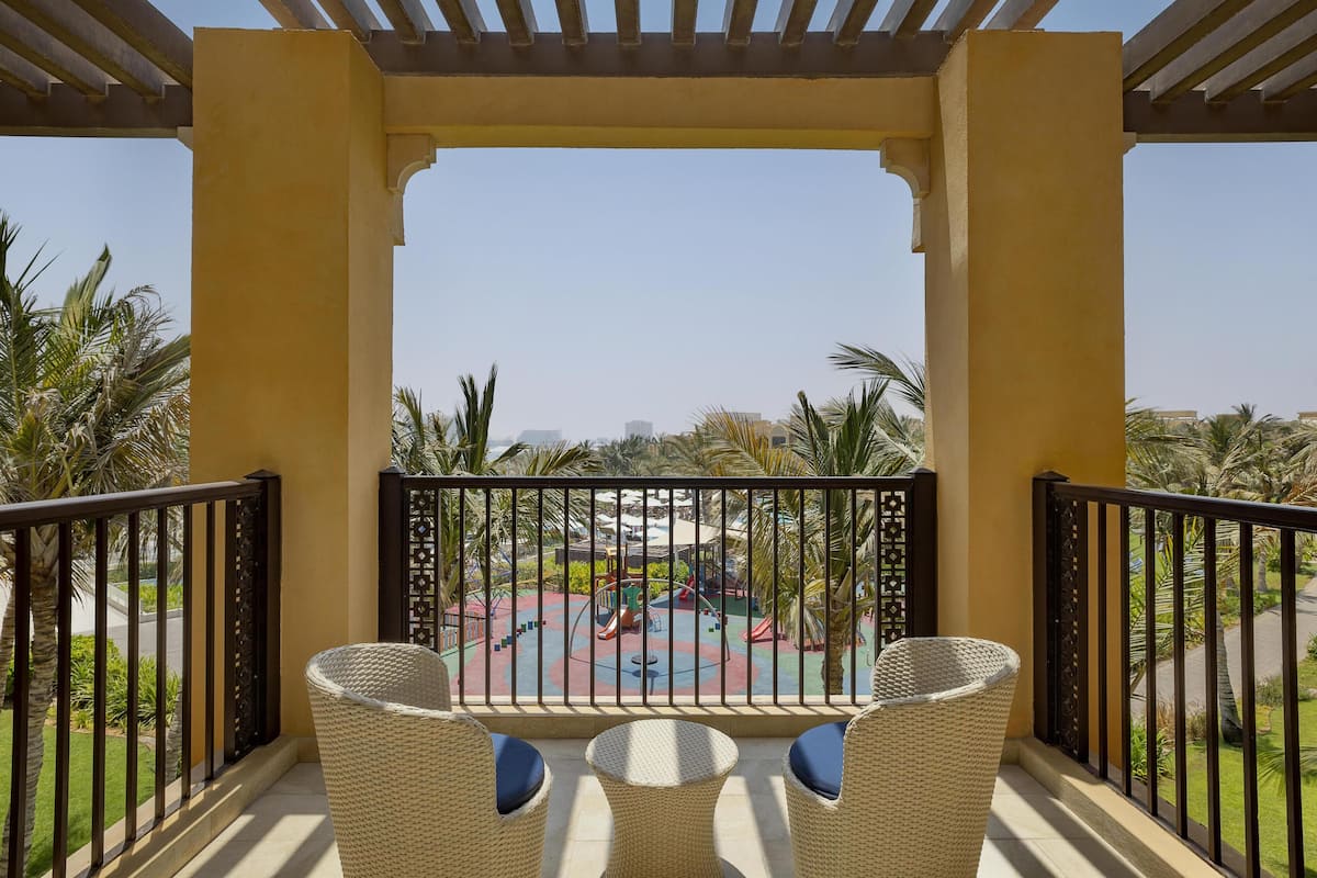 A balcony with wicker chairs and a view of a playground.