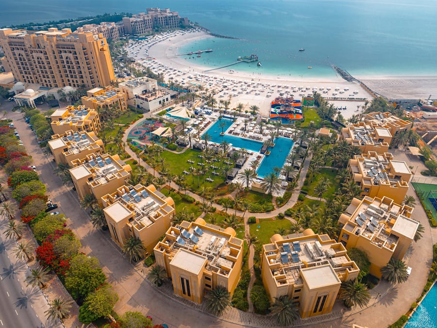 Un complexe hôtelier comprenant plusieurs bâtiments, une plage et une piscine.