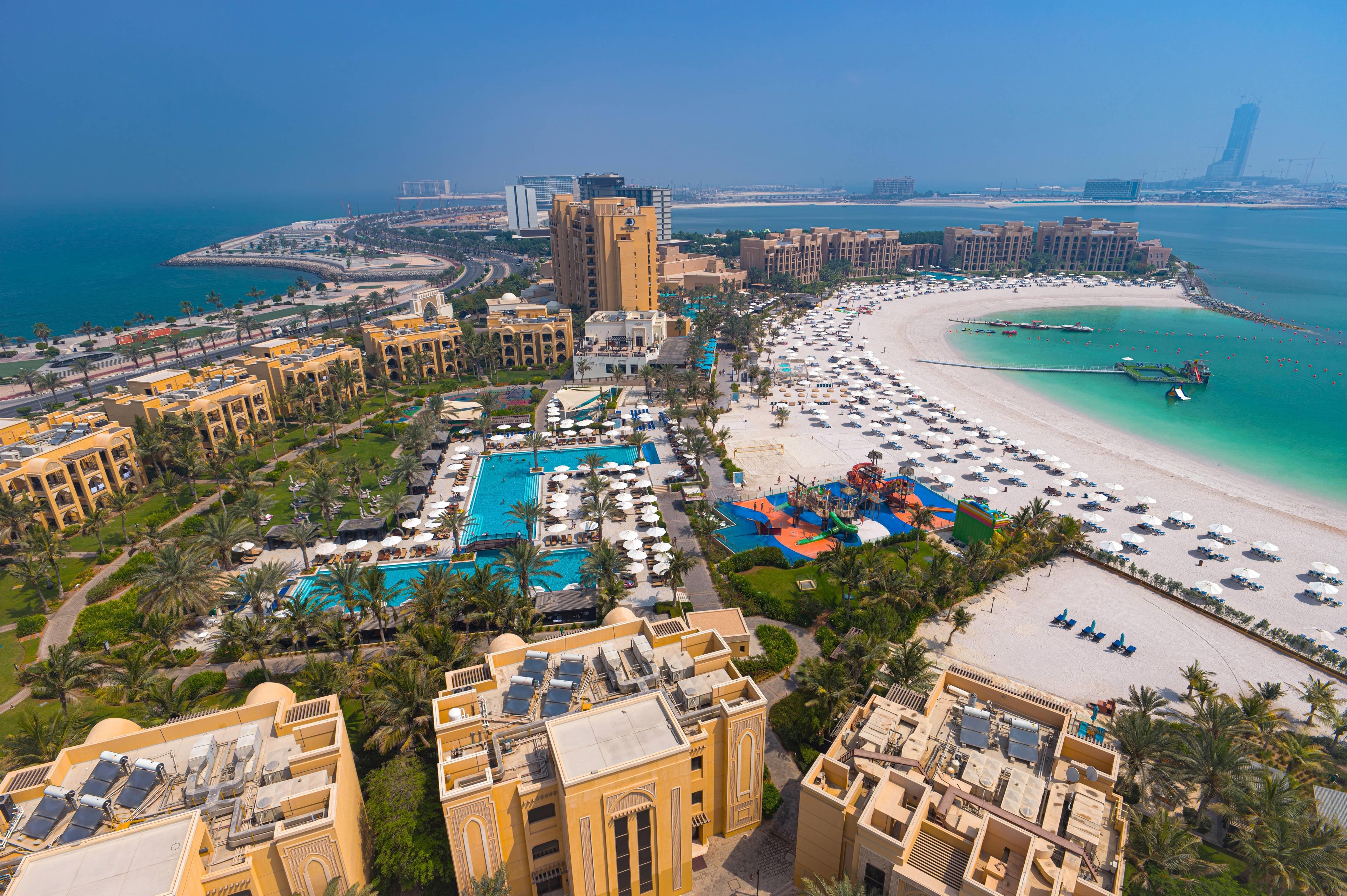 A resort with a large pool, beach, and ocean view.