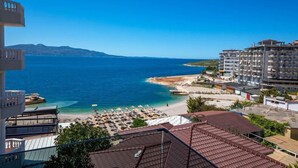 A coastal hotel with a beach view, multiple balconies, and a clear sky. - Apollon Hotel (SARANDE)