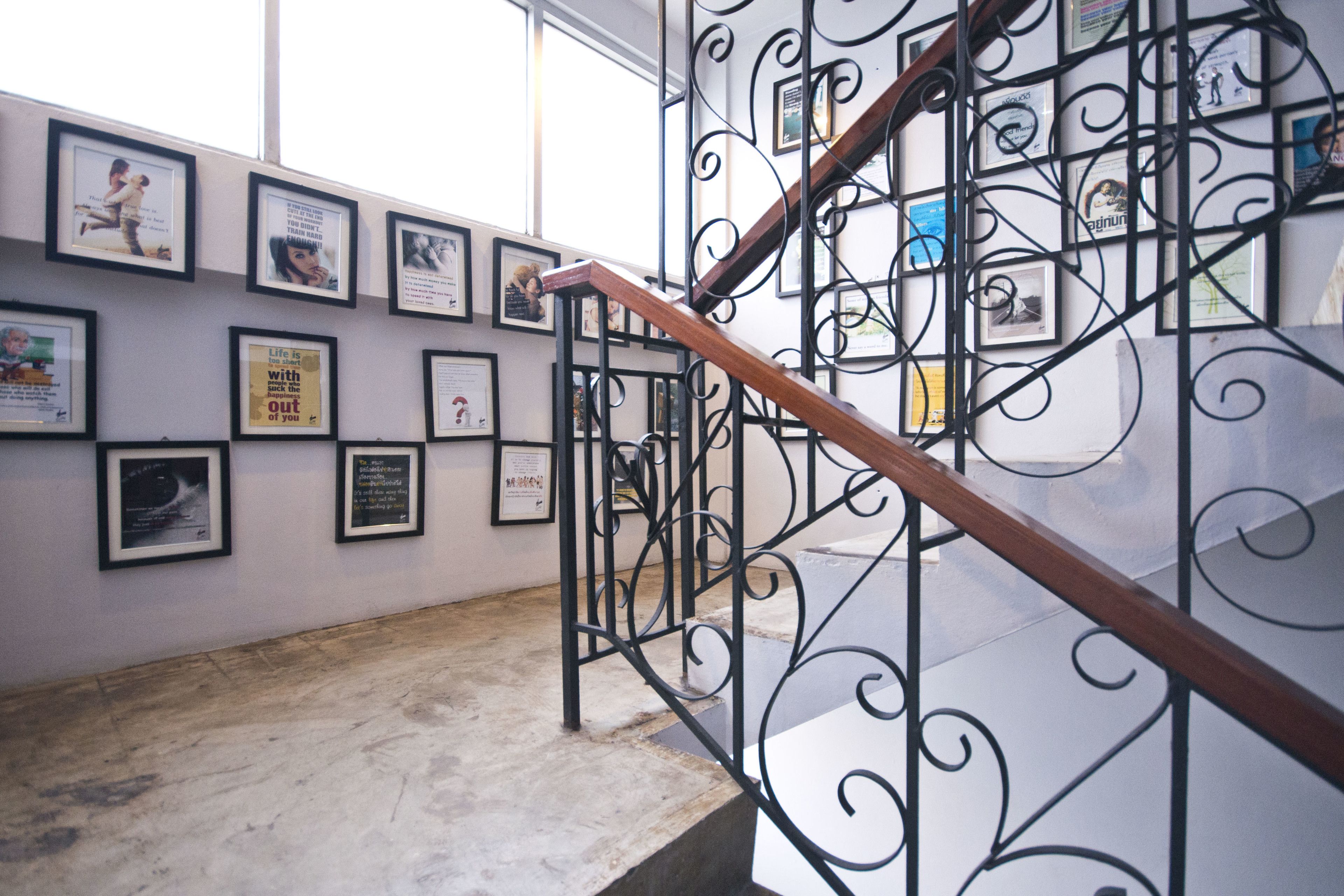A staircase with a wooden handrail and black metal railings, leading to a wall adorned with framed pictures and certificates.