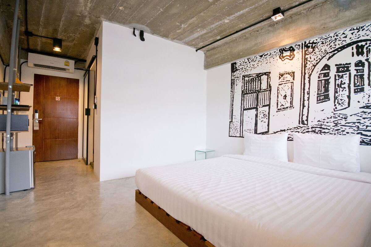 Ein modernes Hotelzimmer mit einem großen Bett, einer Holztür und einem Wandgemälde.