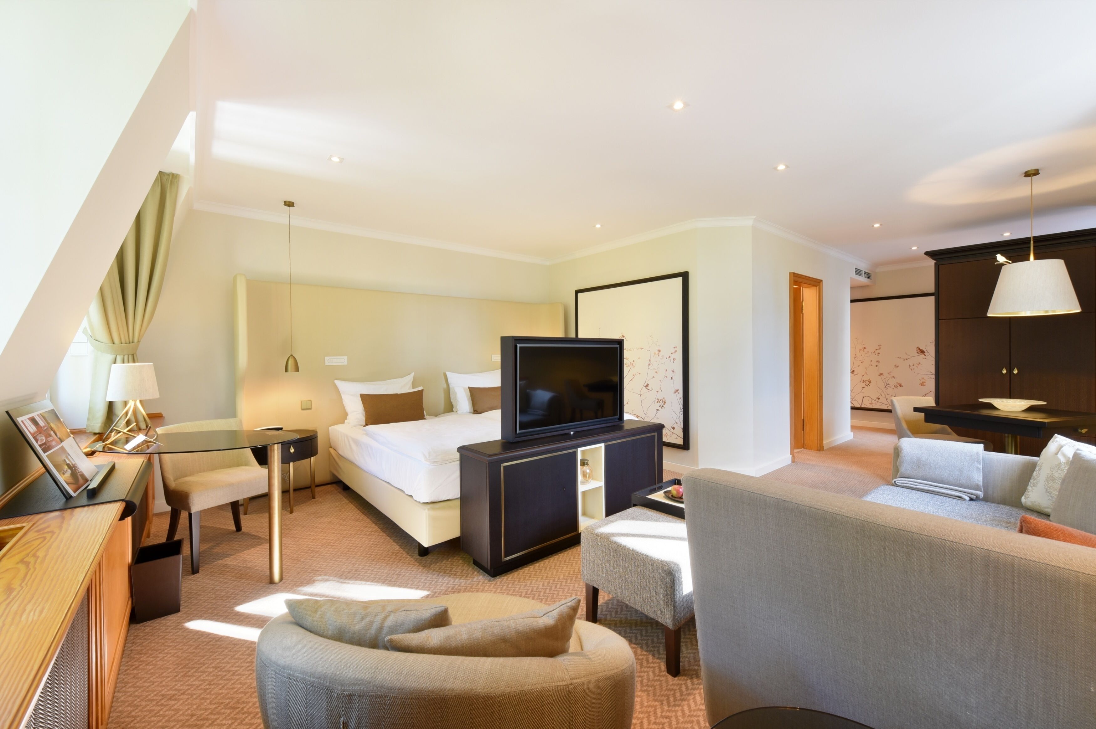 Une chambre d’hôtel moderne équipée d’un lit, d’une télévision, d’un bureau, d’une chaise et d’un canapé.