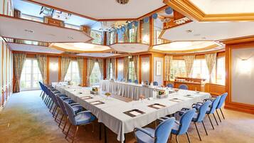 Une salle de conférence avec une longue table, des chaises bleues et une nappe blanche.