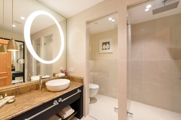 A modern bathroom with a large oval mirror, a sink, and a shower area.