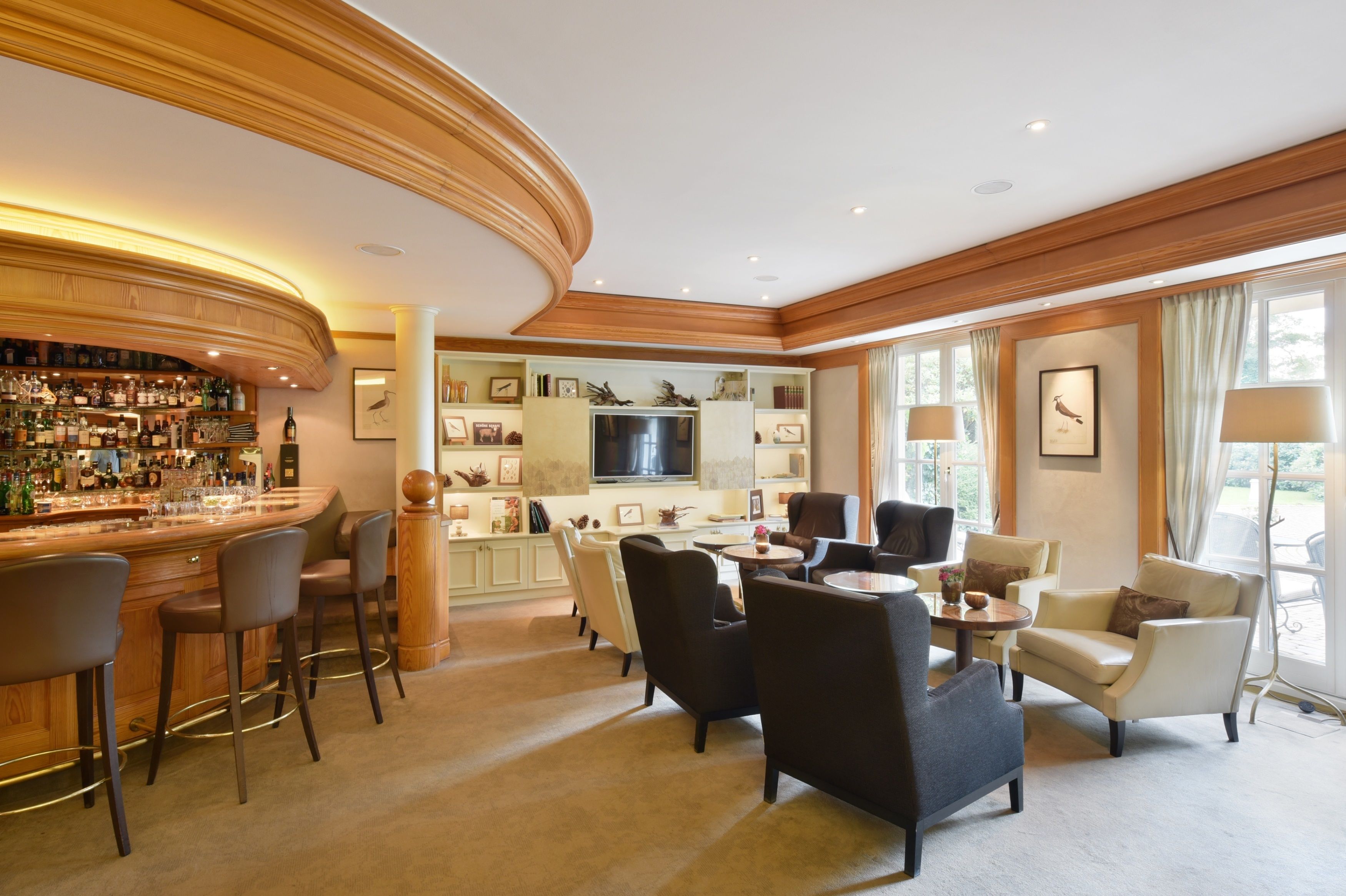 A bar area with stools, a television, and a seating area with chairs and a table.