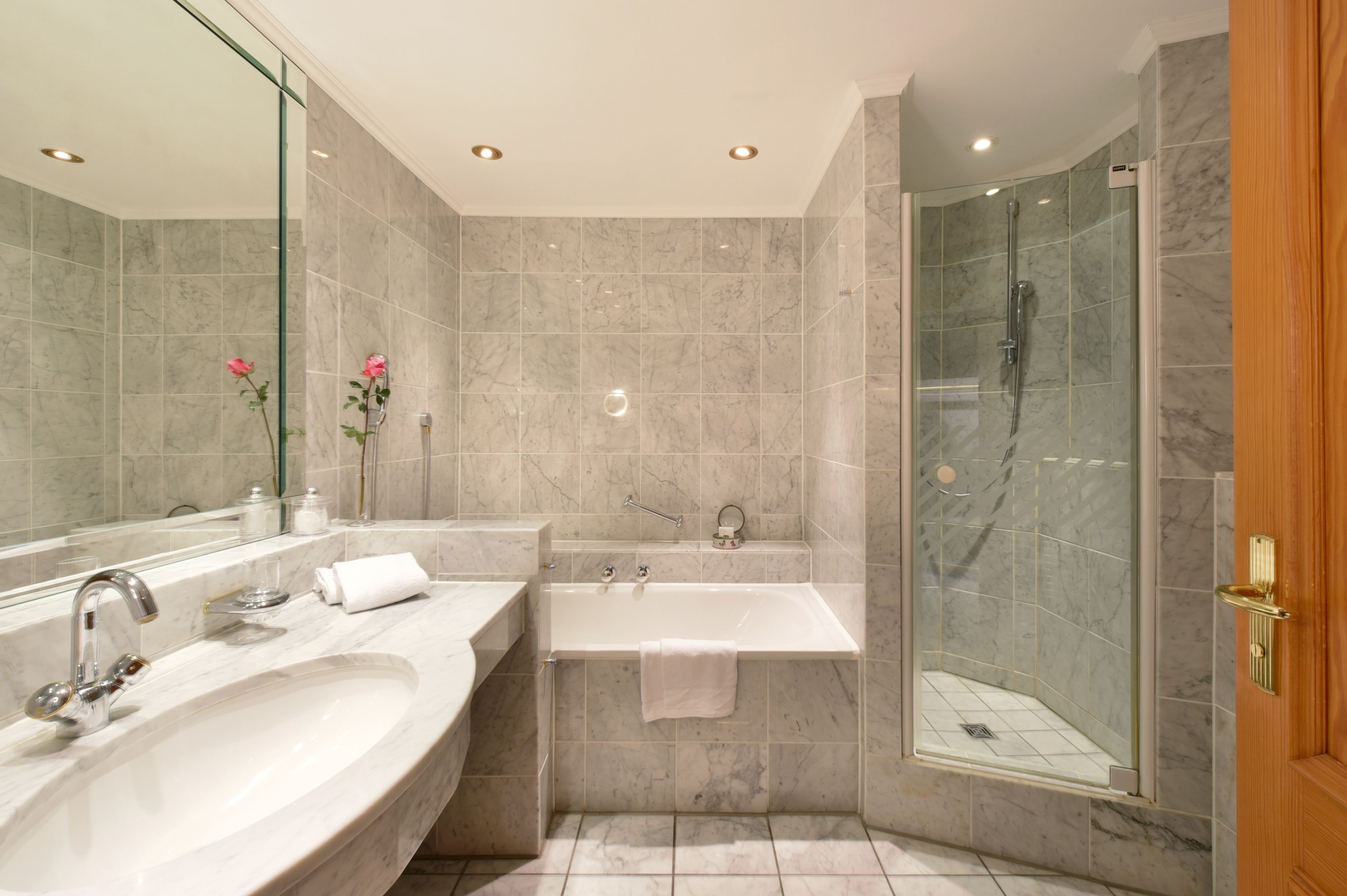 Un baño moderno con un lavamanos grande, tocador doble, bañera y zona de ducha con mampara de vidrio.