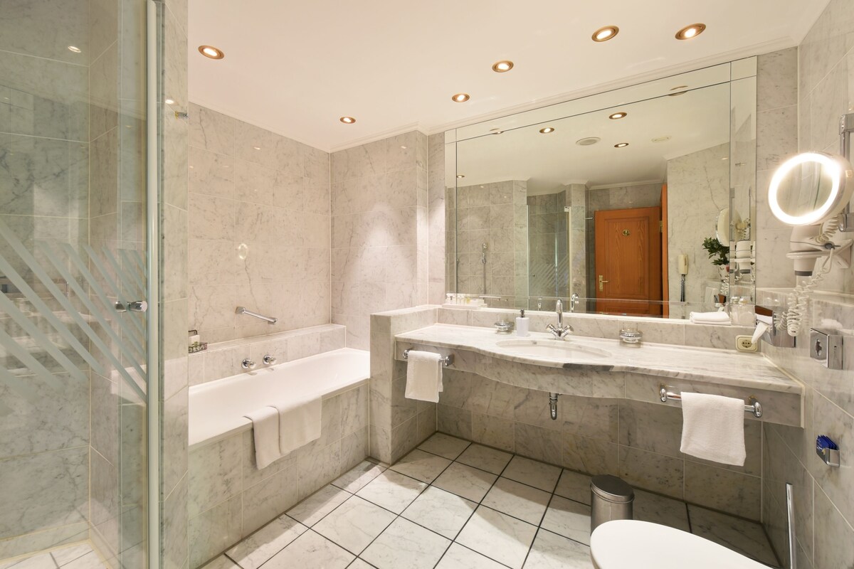 Une salle de bain moderne dotée d’une douche à parois de verre, d’un meuble-lavabo double avec un grand miroir et d’un espace toilettes séparé.