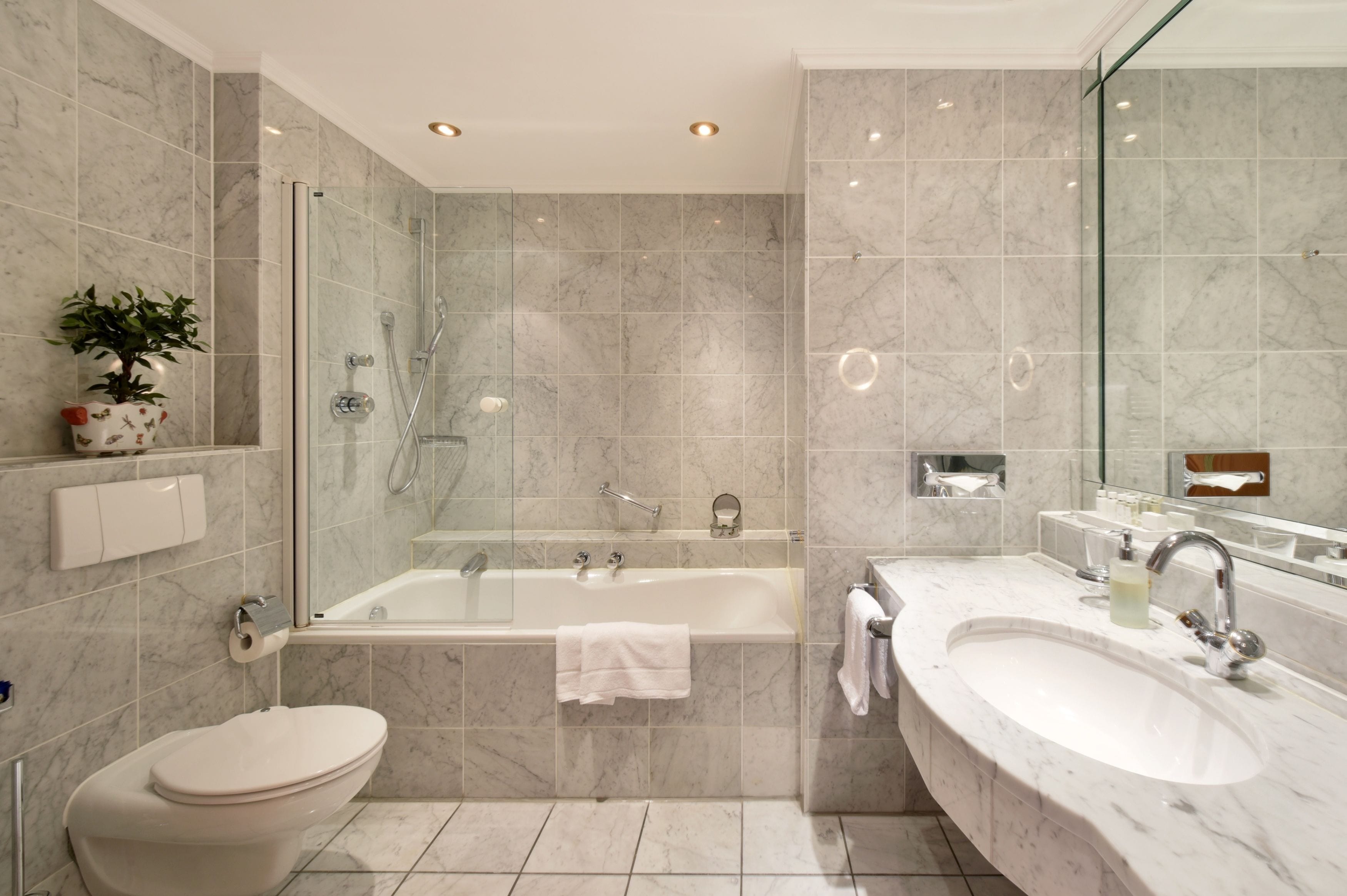 Un baño moderno con ducha de vidrio, bañera independiente, inodoro y tocador con lavabo y espejo.