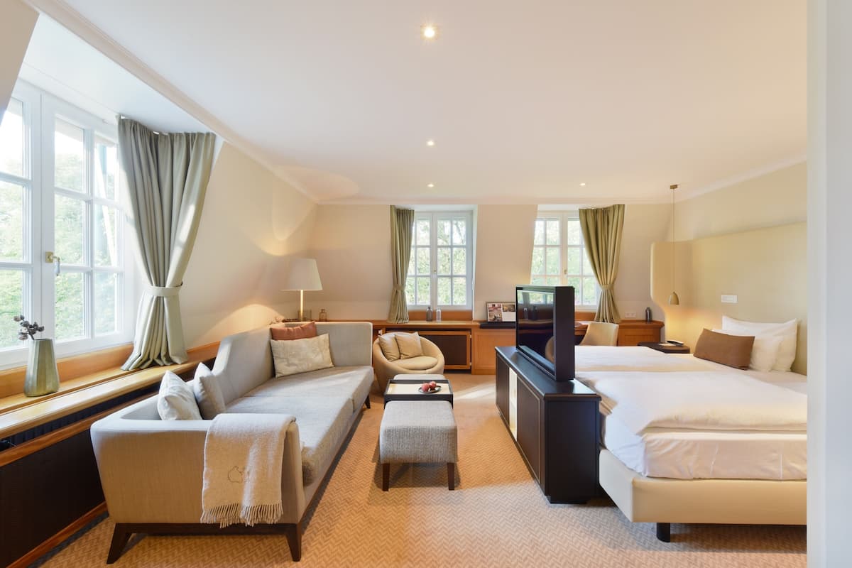 A hotel room with a sofa, a bed, a TV, and a desk.