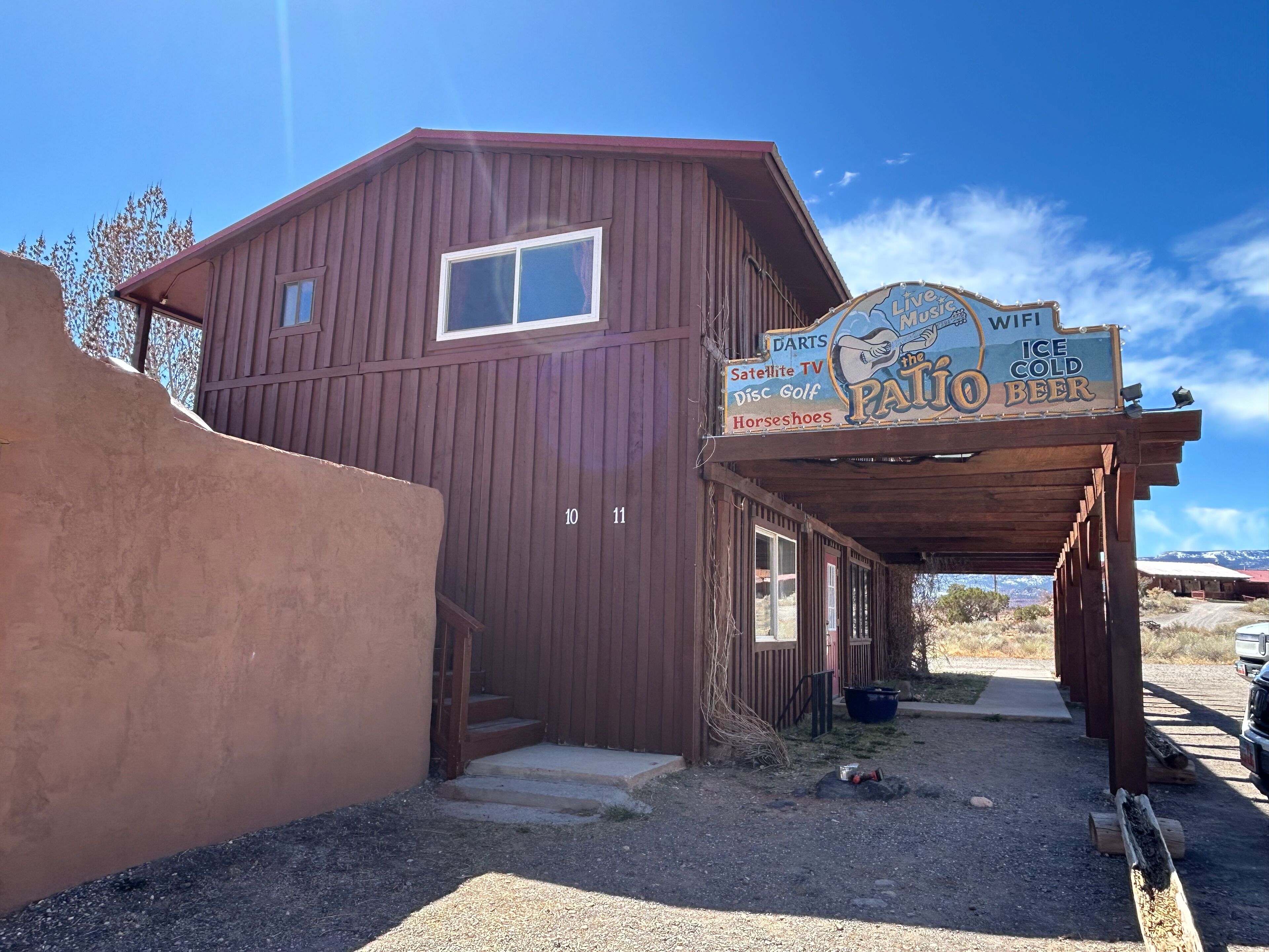 Un bâtiment rustique, agrémenté d’une enseigne annonçant des concerts, des jeux de fléchettes, la télévision par satellite, du disc golf, des jeux de fer à cheval et de la bière bien fraîche.