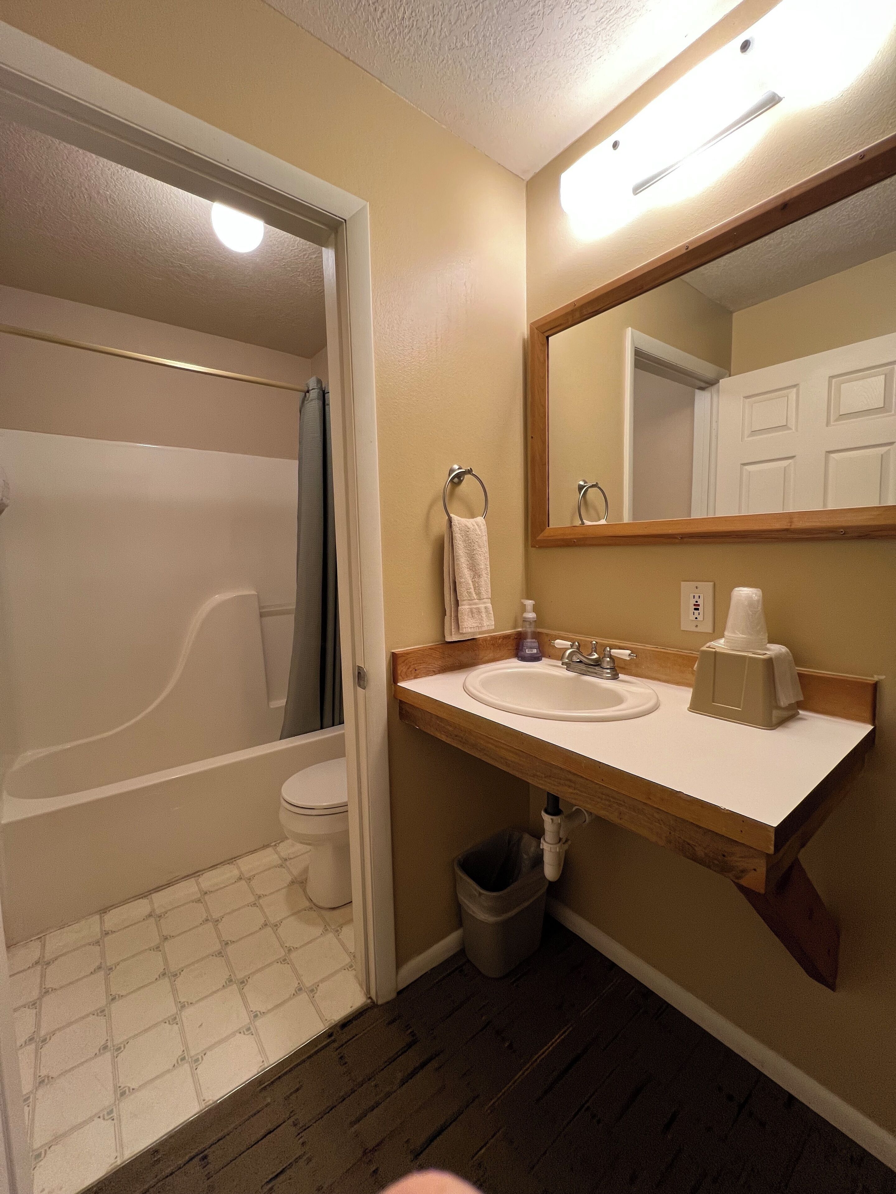 A bathroom with a bathtub, toilet, sink, and mirror.