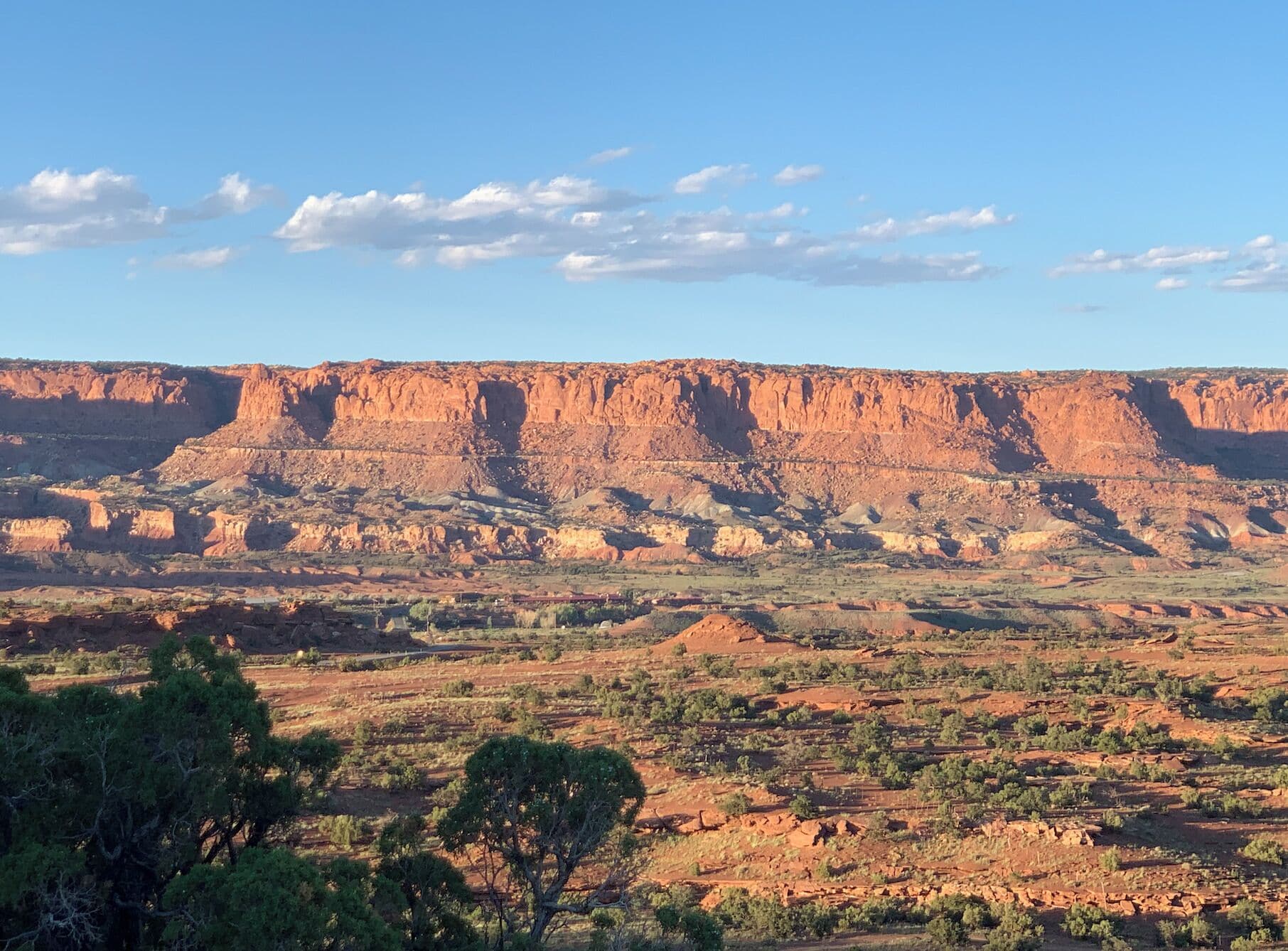 A vast landscape with a prominent red rock formation in the background.