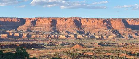 A vast landscape with a prominent red rock formation in the background.