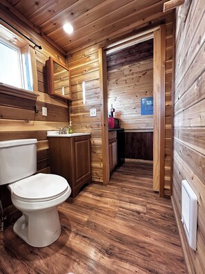 A wooden cabin bathroom with a toilet, sink, and cabinet. - The Rim Rock Inn (Torrey)
