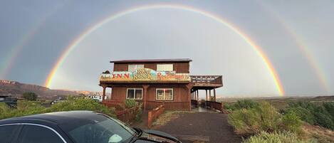 A wooden building with a sign reading "Rim Rock Restaurant" and a car parked in front.