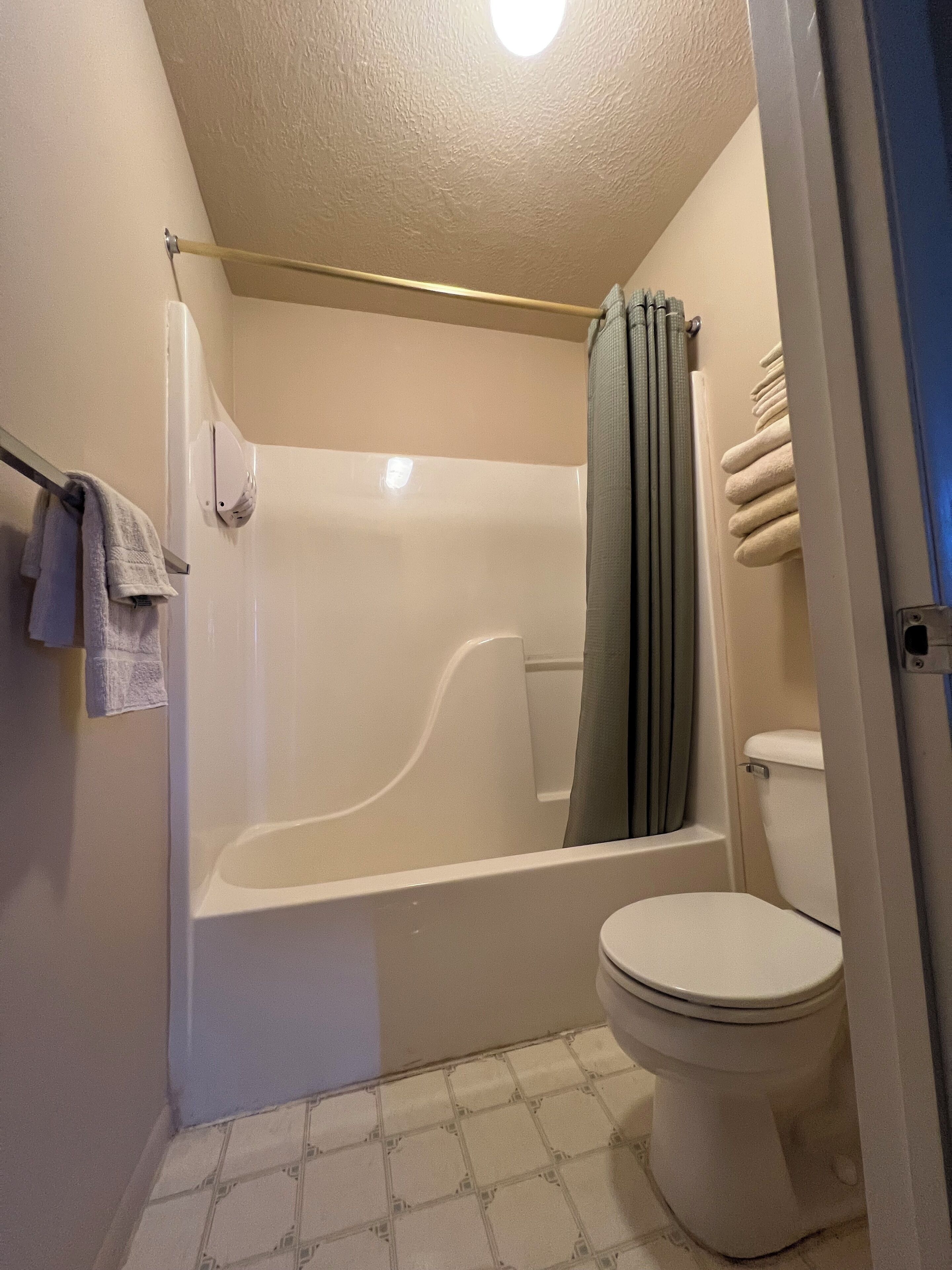 Un baño con bañera, inodoro y cortina de ducha.