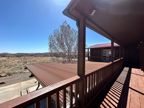 A wooden deck with a view of a mountainous landscape and a tree. - The Rim Rock Inn (Torrey)