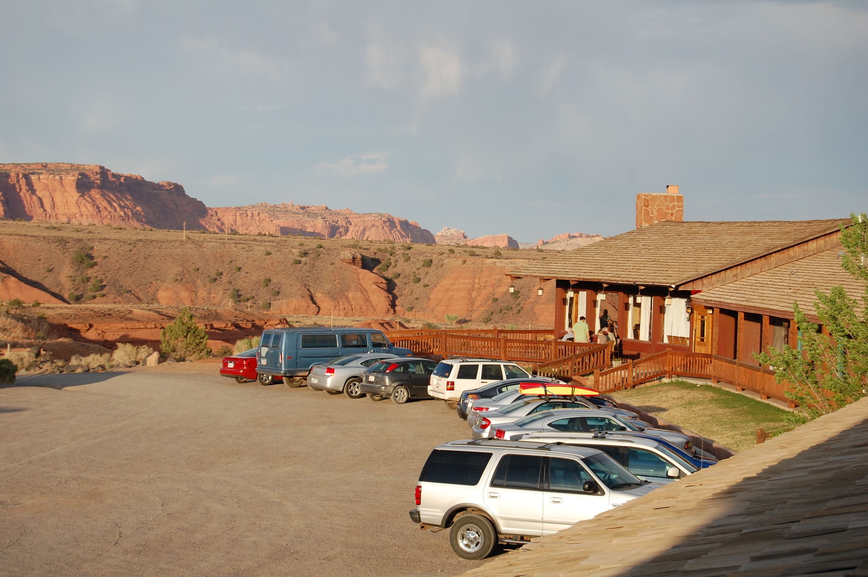 A parking area with several cars and a building with a wooden facade.