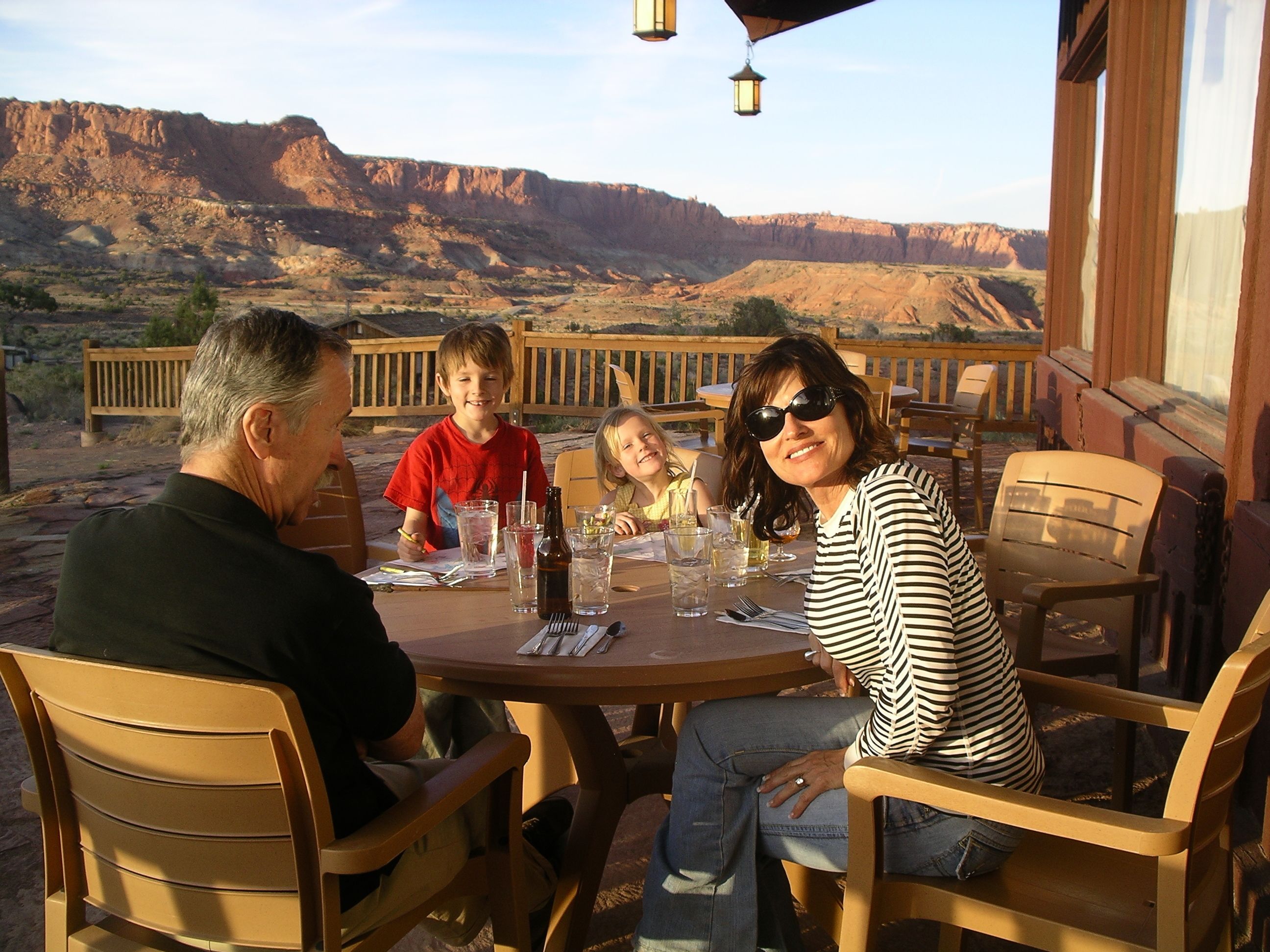 A family dining at an outdoor table with a view of a canyon.