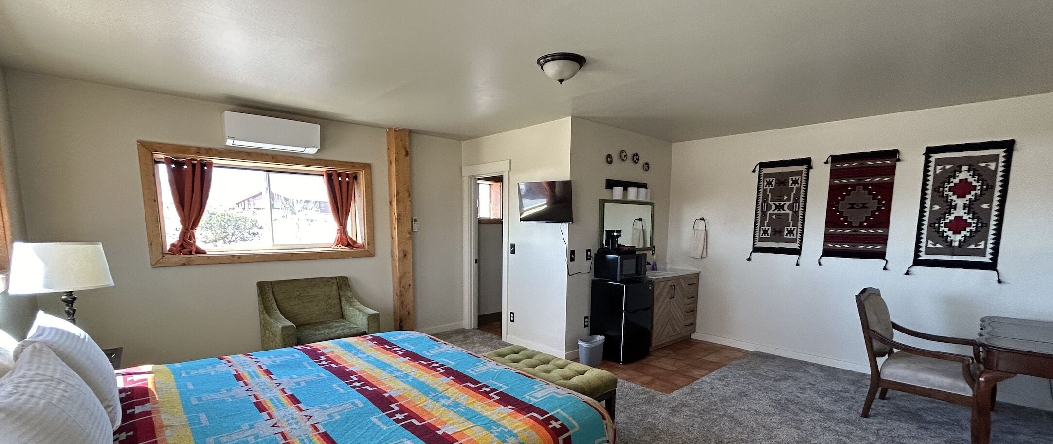 A bedroom with a bed, a chair, a desk, and a wardrobe.
