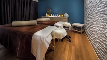 Relax in this serene spa room with two comfortable beds, a wooden desk, and a peaceful atmosphere.