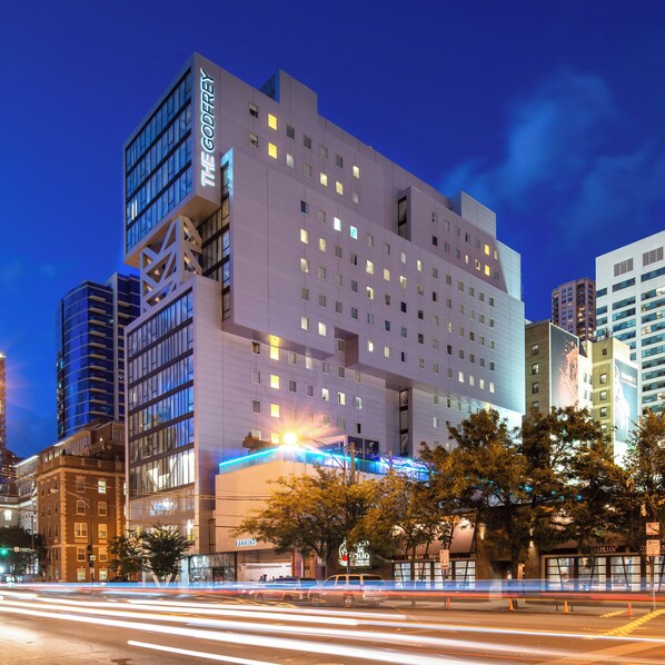 A modern hotel with a prominent sign, multiple floors, and a parking area in front. - The Godfrey Hotel Chicago (Chicago)