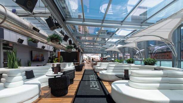 A modern rooftop lounge with white seating, a glass ceiling, and city views. - The Godfrey Hotel Chicago (Chicago)