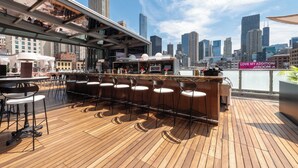 A rooftop bar with a city skyline view, wooden flooring, and bar stools. - The Godfrey Hotel Chicago (Chicago)