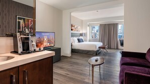 A modern hotel room with a cityscape view, a bed, a desk, a coffee machine, and a purple sofa. - The Godfrey Hotel Chicago (Chicago)