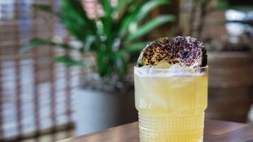 A glass of yellow beverage with a garnish on a wooden table.