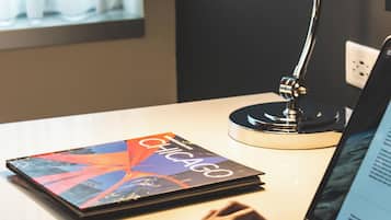 A desk with a laptop, a book, and a desk lamp.